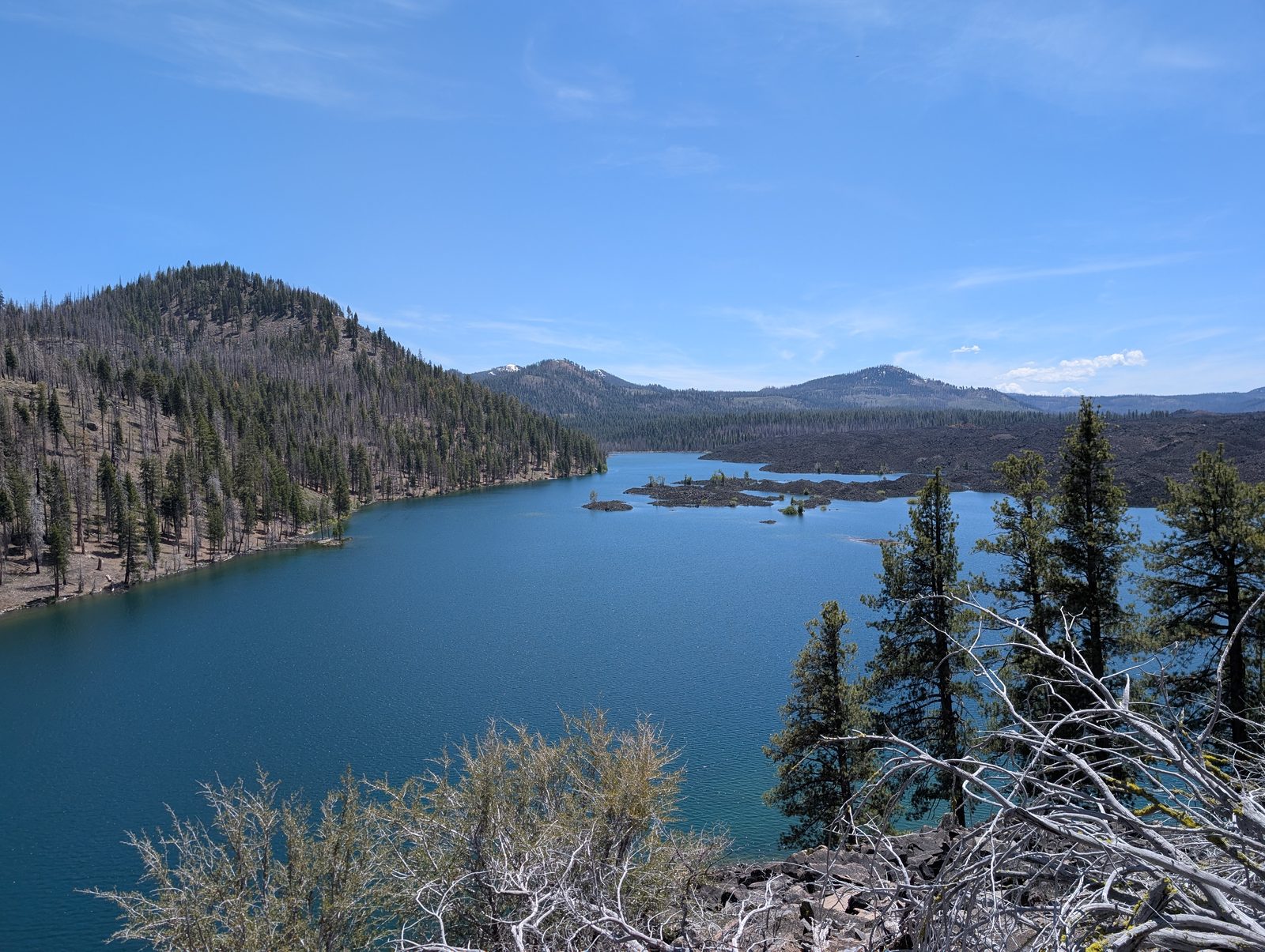 Butte Lake with its deep blue water bordered by a lava flow and distant peaks