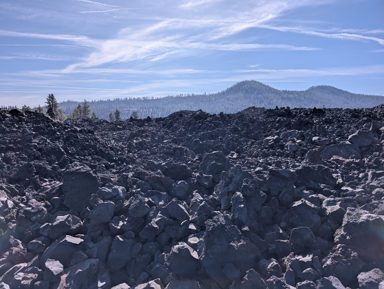 The Fantastic Lava Beds, a field of dark volcanic rock stretching toward forested hills