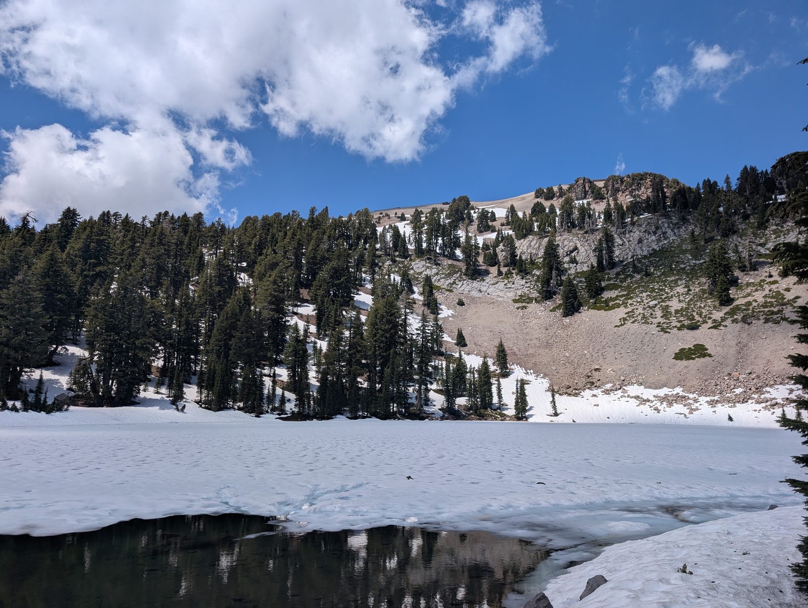 Frozen Lake Helen with snowy peaks and pine trees reflected in the open water