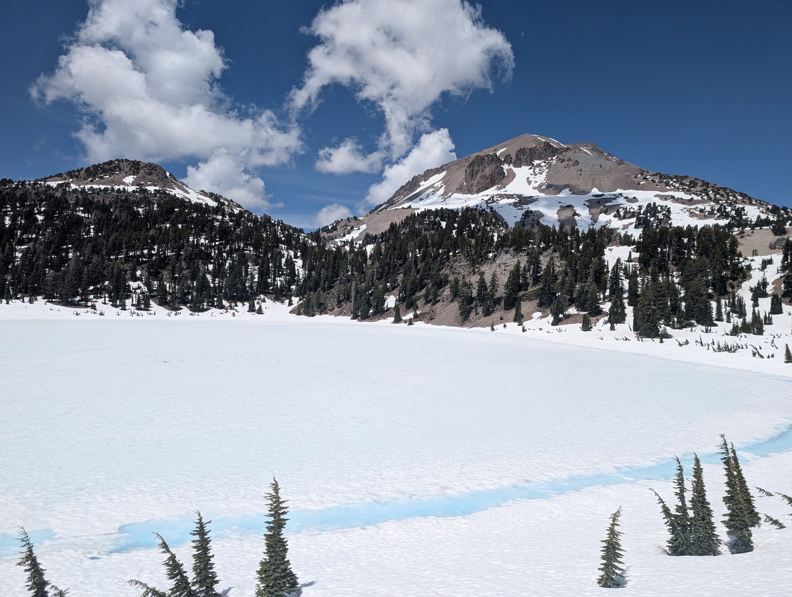 Lassen Peak and a neighboring summit rising above the frozen surface of Lake Helen