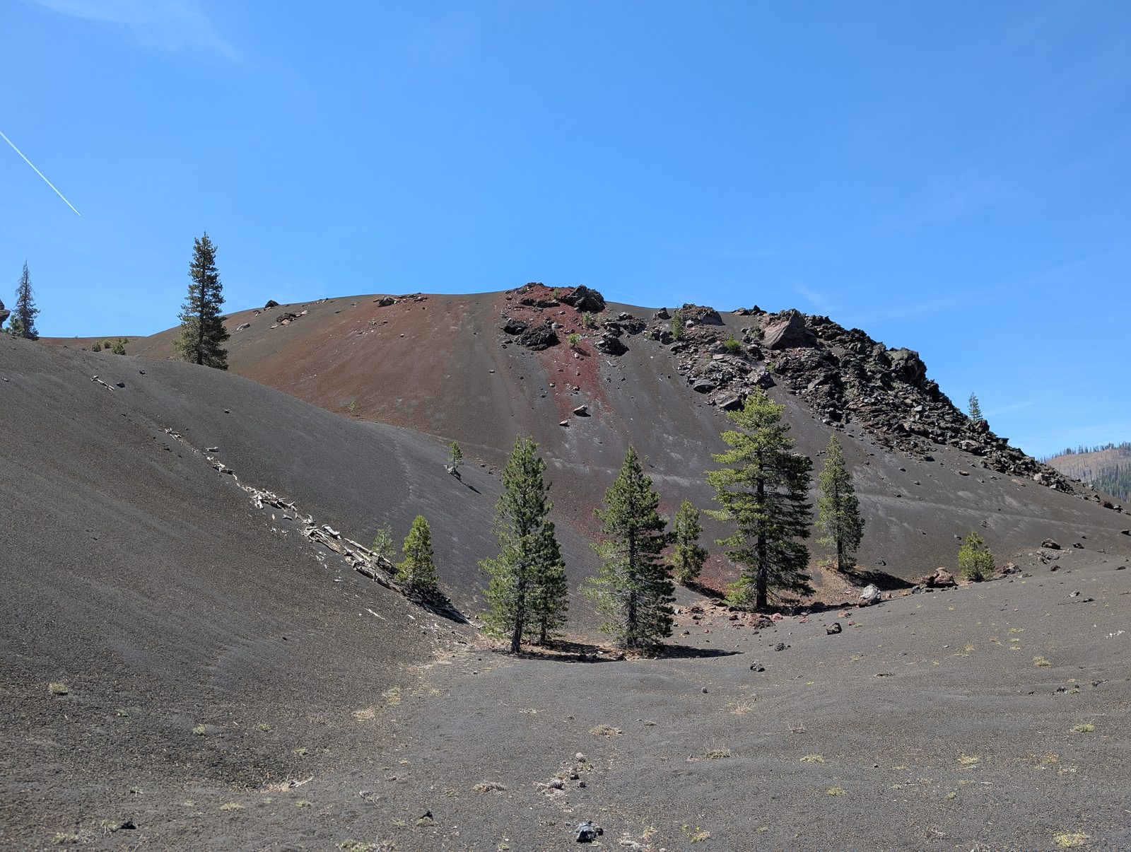 The reddish, oxidized slopes of the Painted Dunes dotted with scattered pines