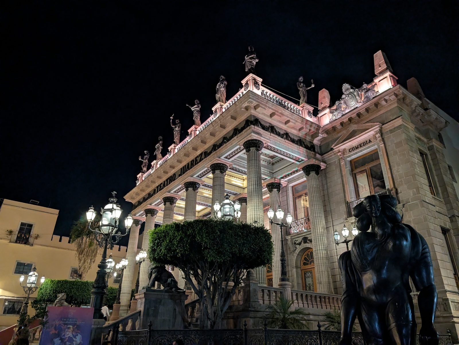 Teatro Juárez illuminated at night, its neoclassical facade topped with statues