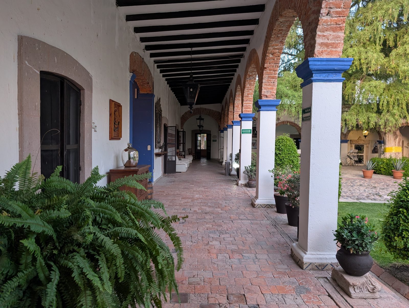 A colonial-era corridor with brick arches and blue-painted columns at the hacienda